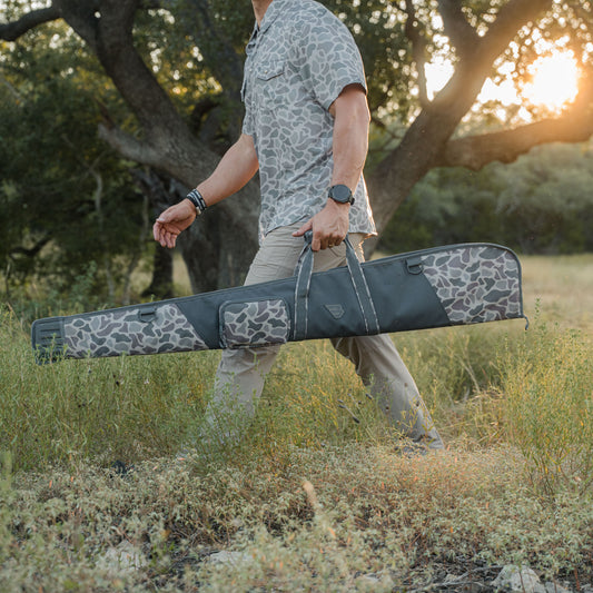 Man walking outdoors with a camouflage-patterned gun case