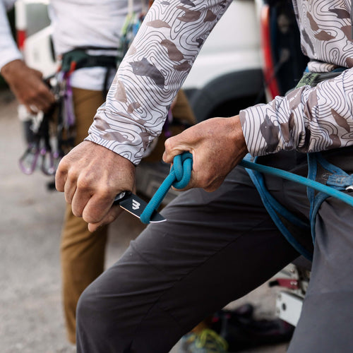 Climber cutting a blue rope with the Classic Deer Camo Everyday Carry Knife