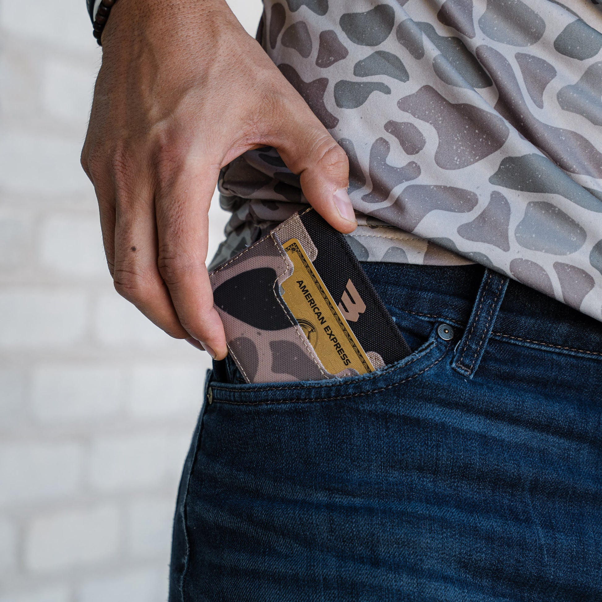 Person inserting a camouflage-patterned card into their pocket