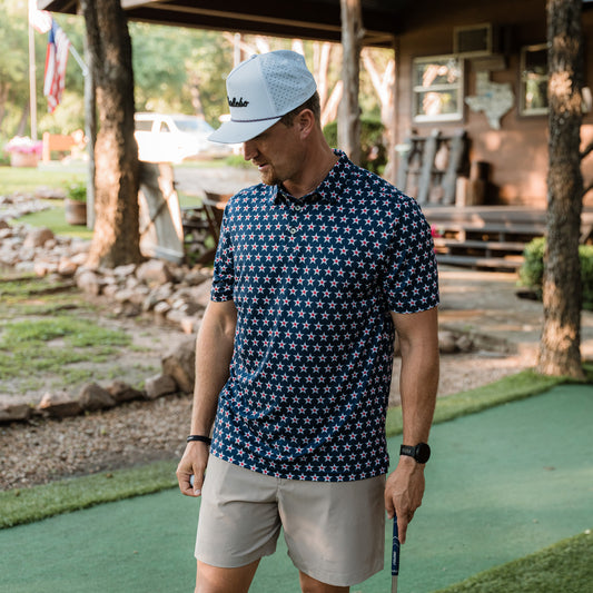Man in a star-patterned shirt and cap standing on a putting green.