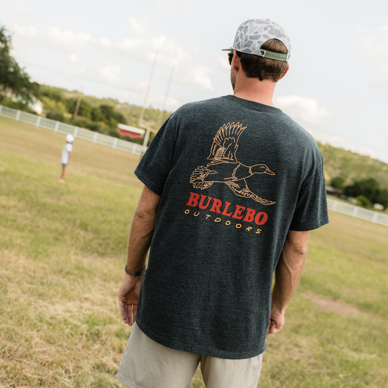 Man wearing a dark gray t-shirt with 'Burlebo Outdoors' logo outdoors.