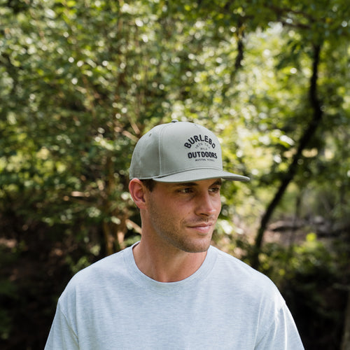 Man wearing a cap with 'Burley Outdoors' logo in a forest setting