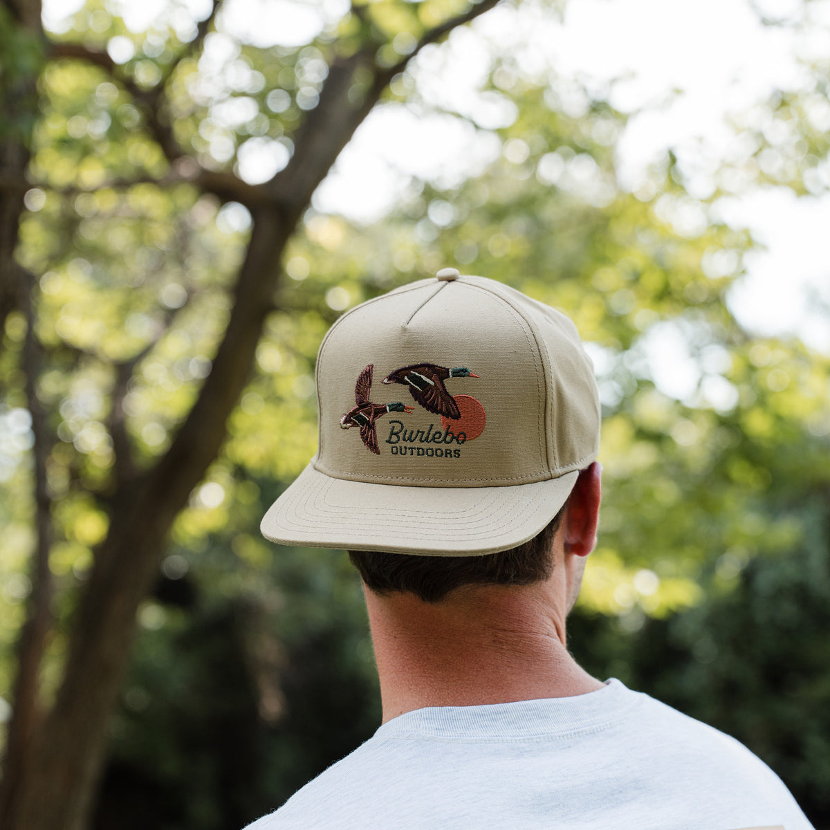 Person wearing a beige cap with a logo outdoors