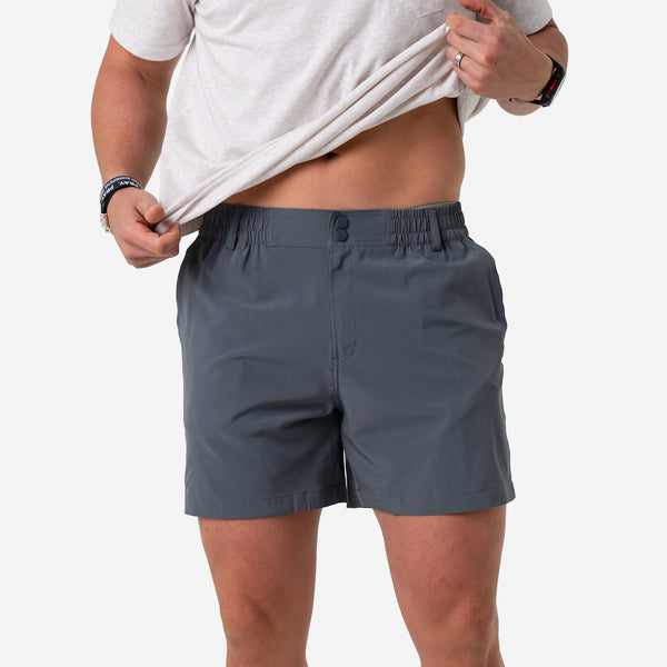 Man lifting his tee to show the River Rock Grey Everyday Short with snap waistband, front view
