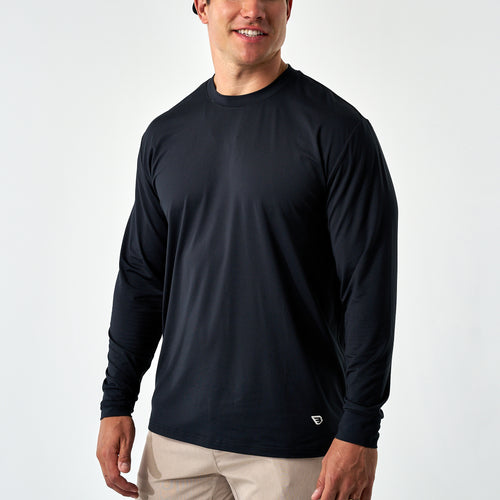 Smiling man wearing the Black Long Sleeve Go To Tee with khaki pants, front view on a white background
