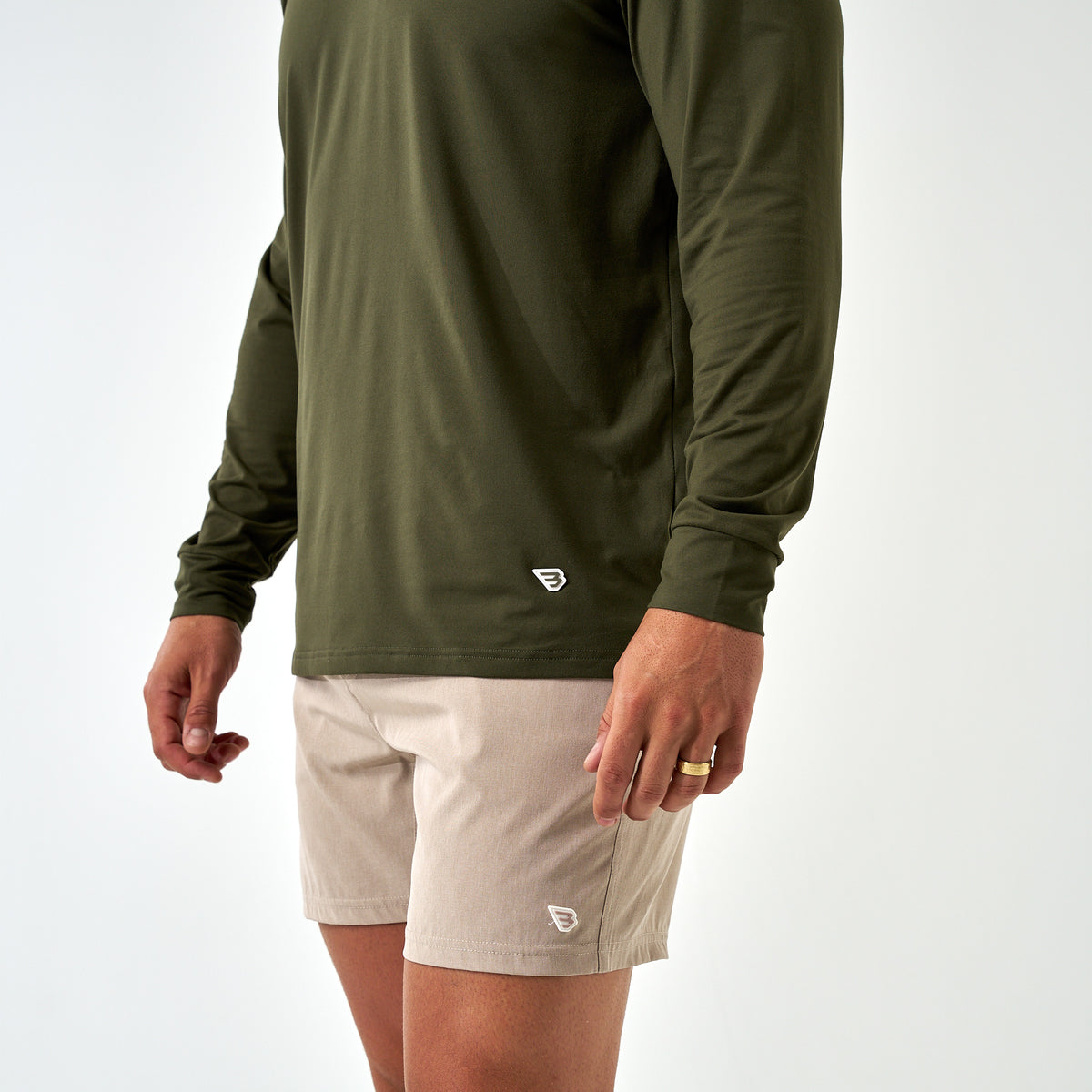 Close-up of the Mallard Green Long Sleeve Go To Tee hem with a small white B logo, worn with khaki shorts