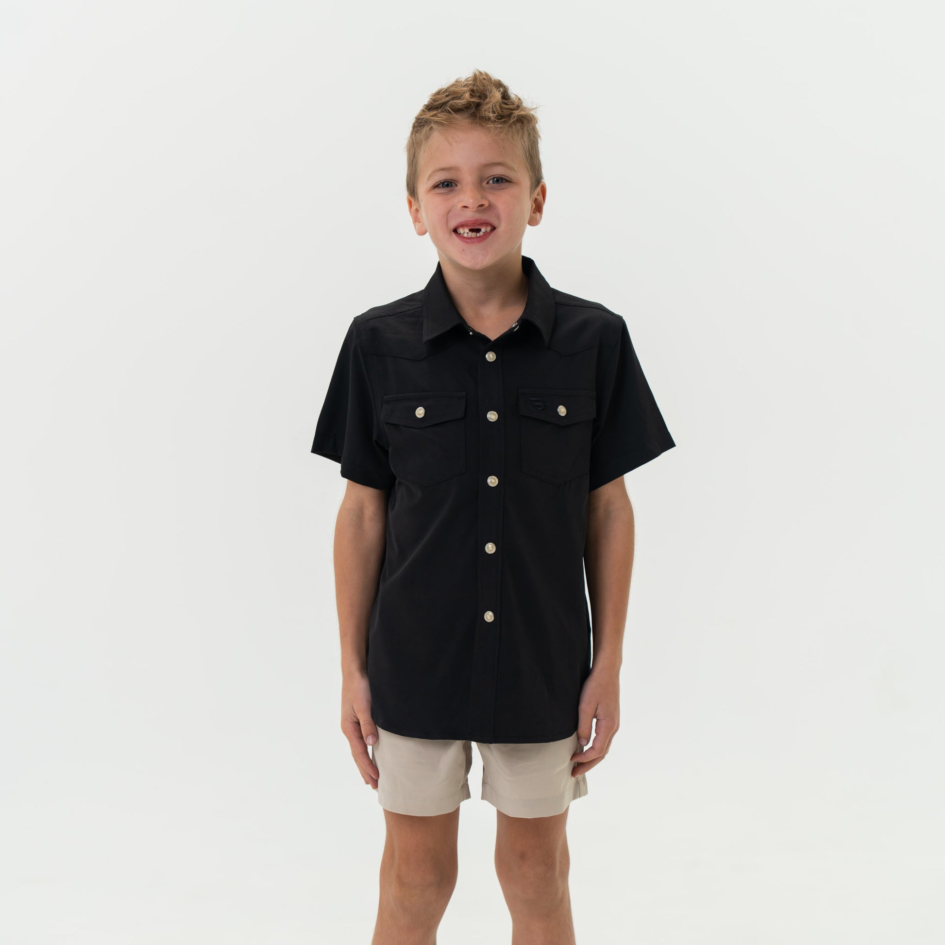 Child wearing a black short-sleeve shirt with buttons on a white background