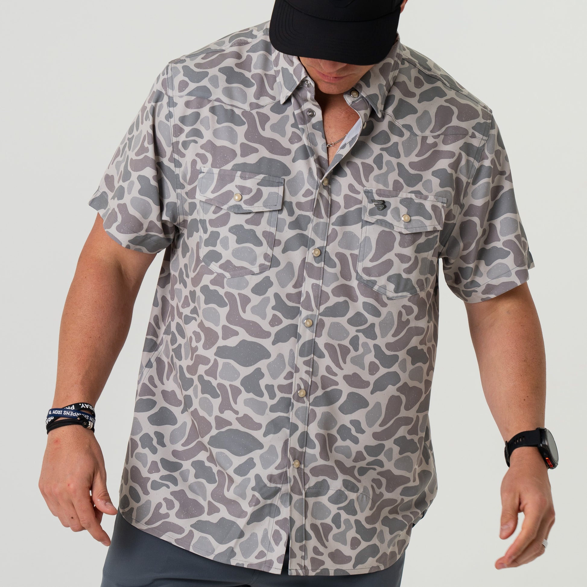 Person wearing a camouflage shirt on a plain background