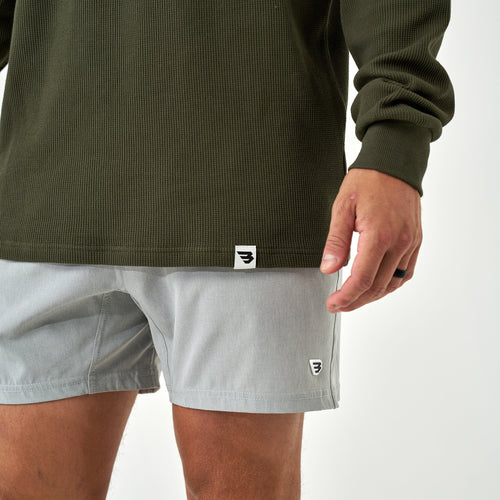 Close-up of the Mallard Green Thermal Hoodie hem tag and cuff over grey shorts