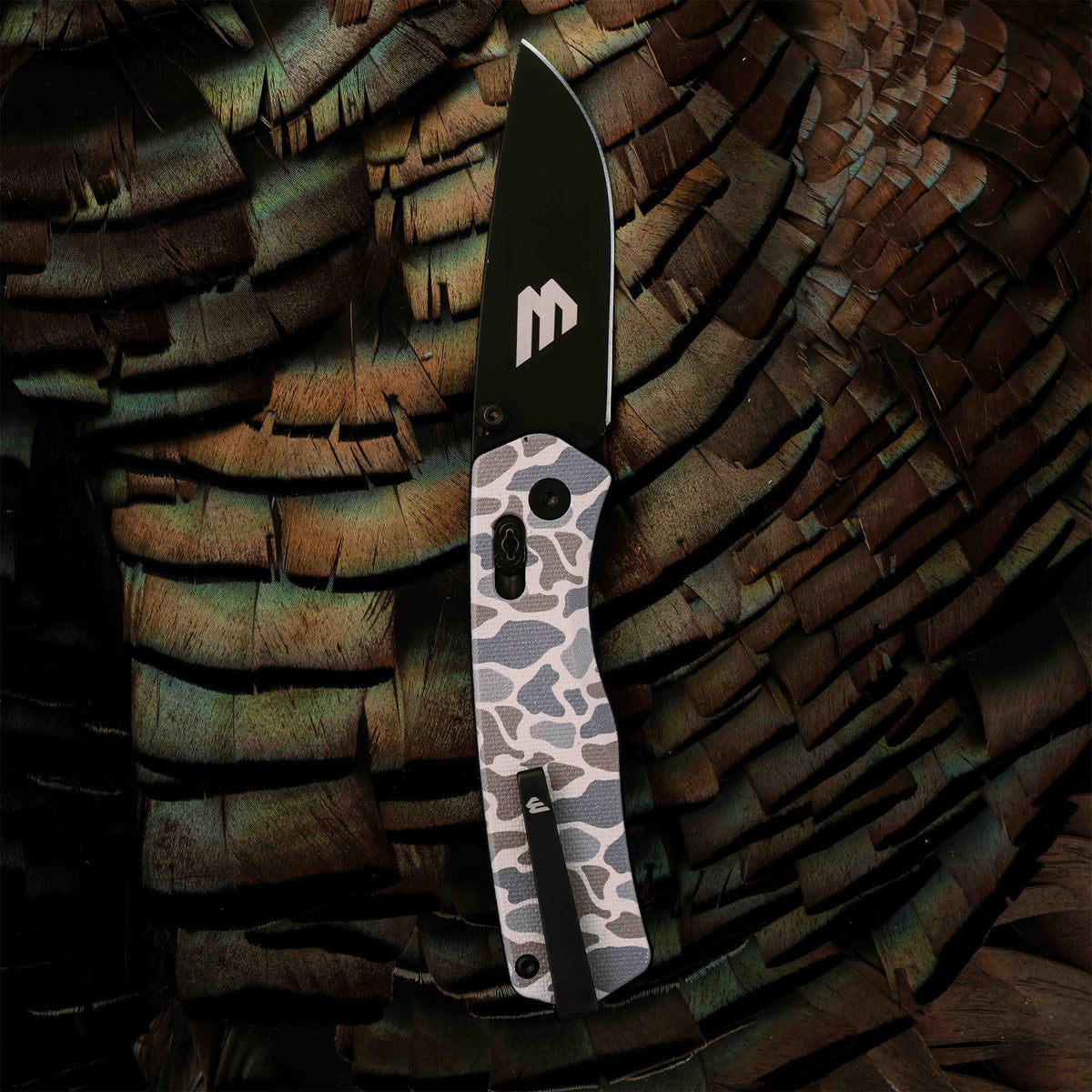 Open Classic Deer Camo Everyday Carry Knife from Williams Knife Co laid on turkey feathers