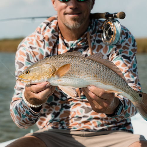 Man holding a fish on a boat with water in the background