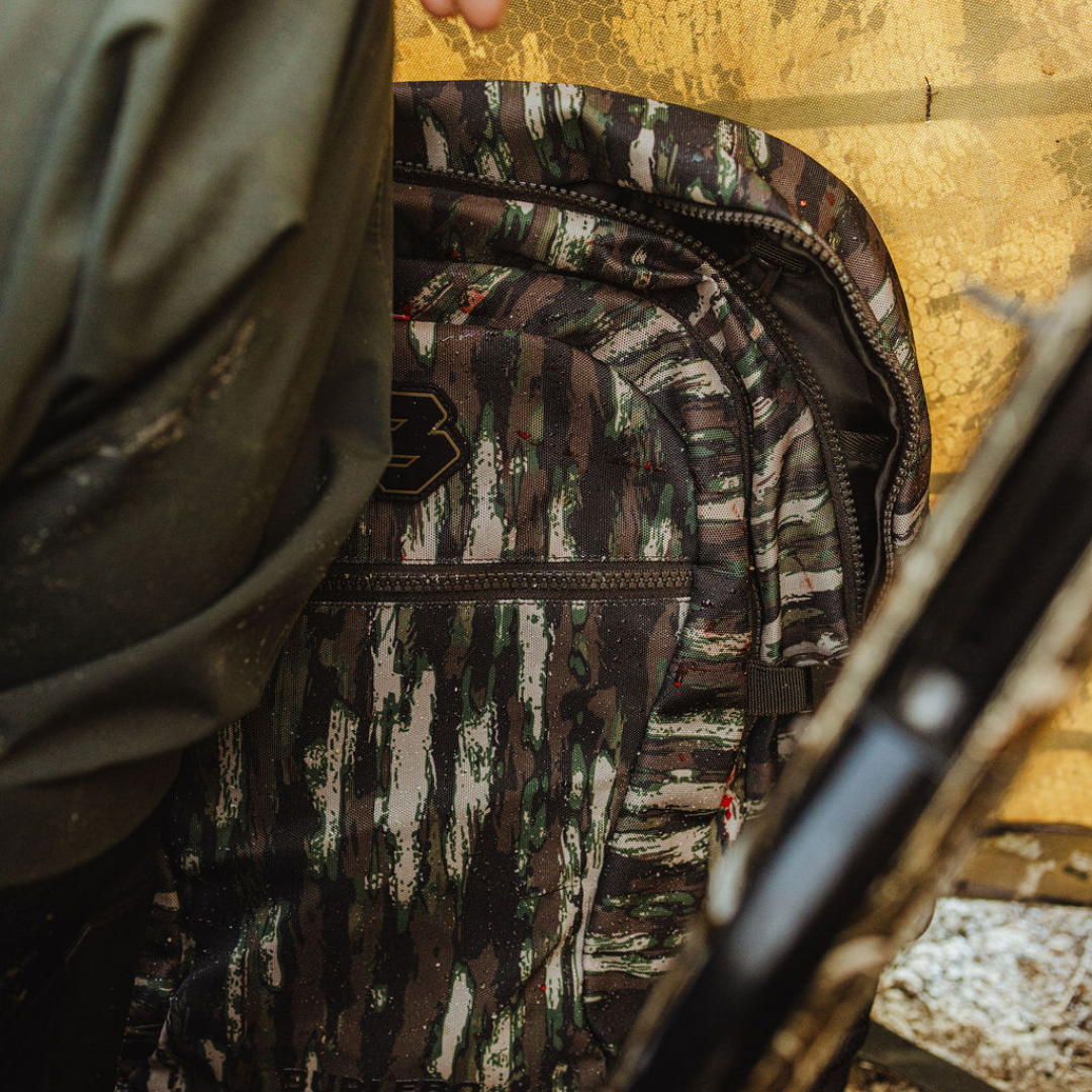Camouflage backpack with a rifle inside, on a natural background