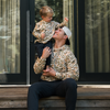Man and child in matching leopard print outfits sitting on steps outside a house.