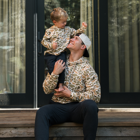 Man and child in matching leopard print outfits sitting on steps outside a house.