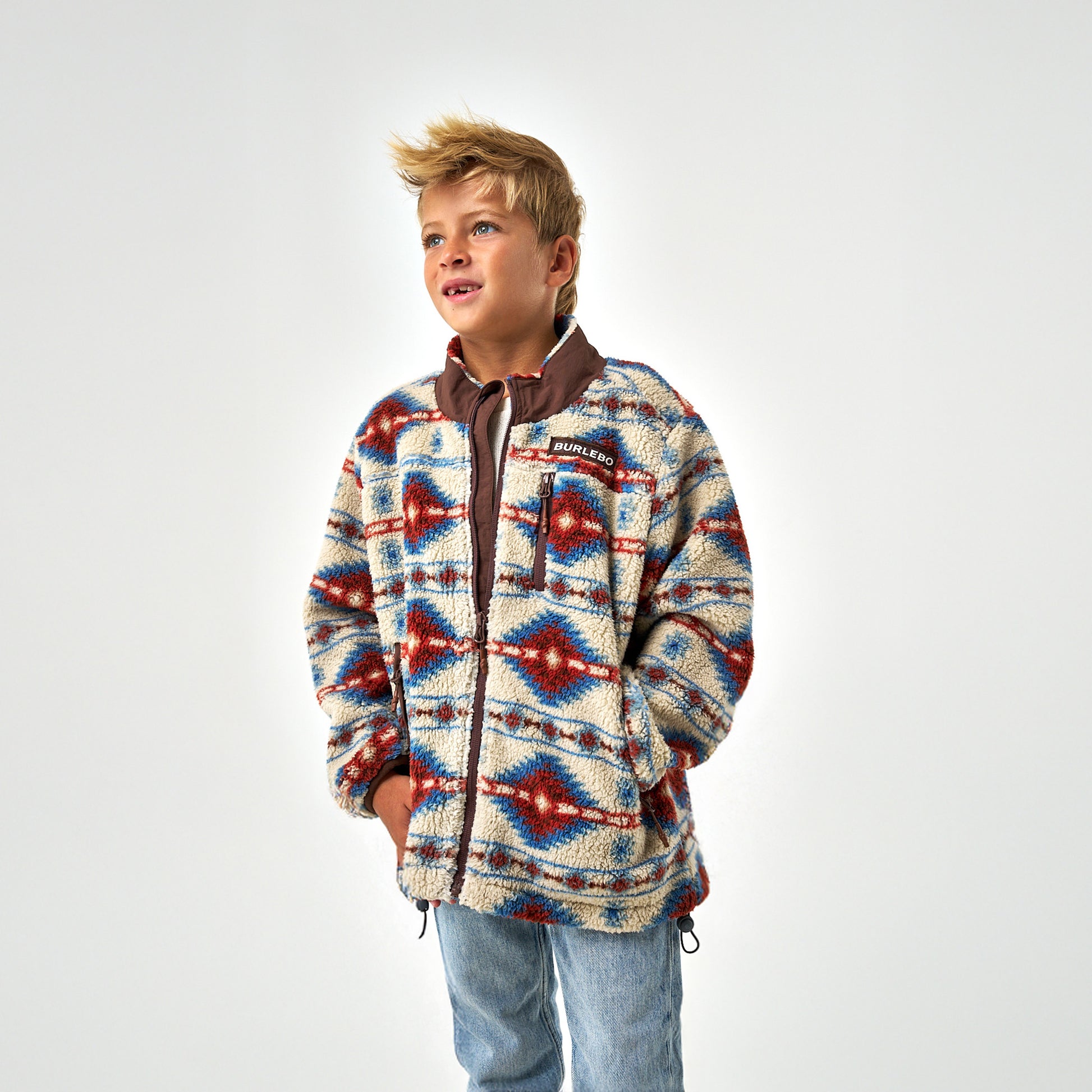 Child wearing a patterned jacket on a white background