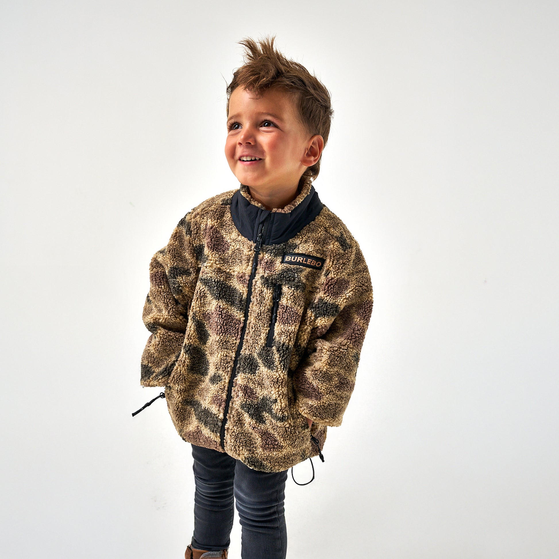 Child wearing a camouflage jacket on a white background