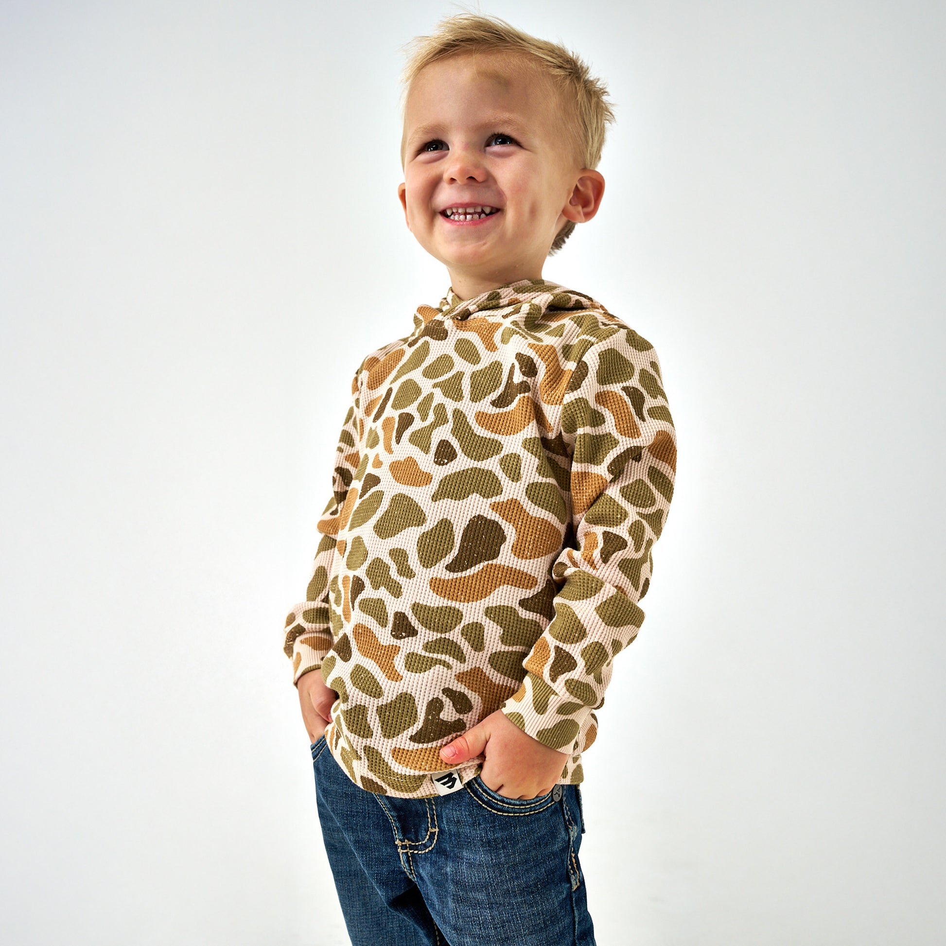 Child wearing a camouflage-patterned hoodie on a white background